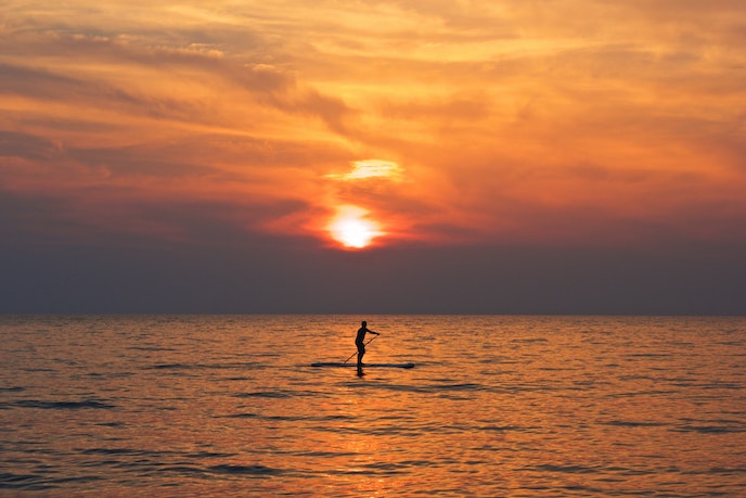 man paddleboarder SUPing at sunset