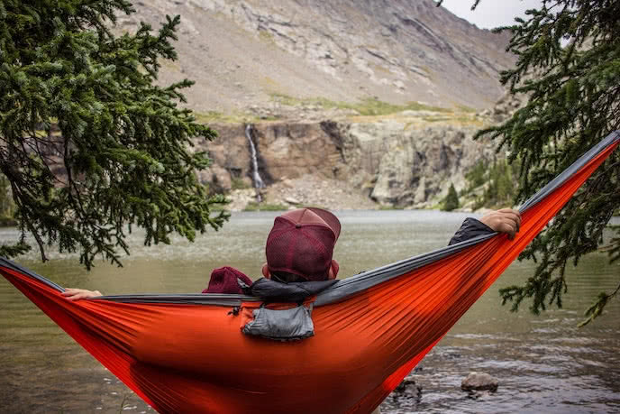 man wild camping with hammock in the wilderness