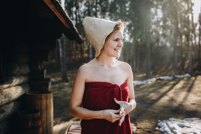 woman with towel and hat outside finnish sauna
